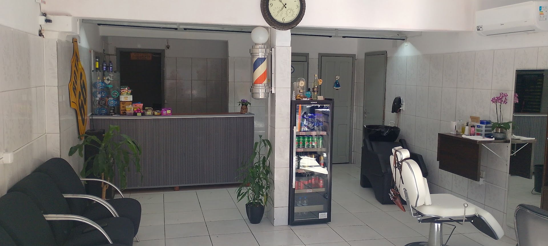 Salão da barbearia com o poste de barbeiro e as cadeiras de atendimento